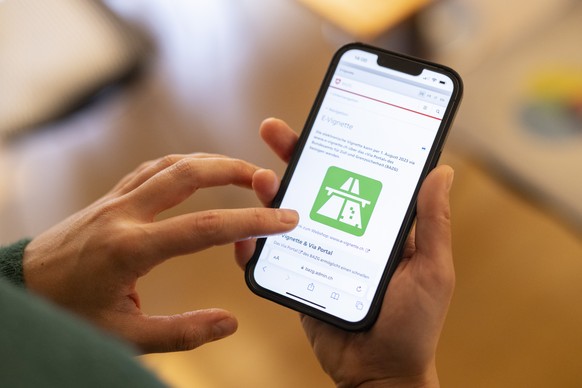 Eine Frau loest eine elektronische Vignette, die E-Vignette, zur Nutzung von abgabepflichtigen Autobahnen und Autostrassen fuer das Jahr 2024 auf ihrem Telefon, aufgenommen am Freitag, 1. Dezember 202 ...