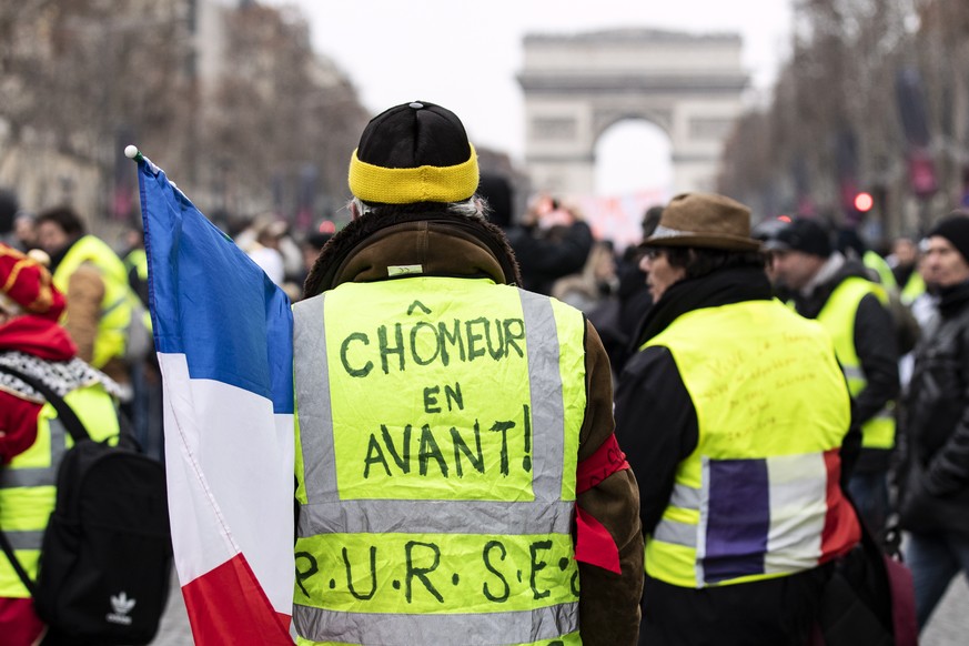 epa07263314 A protester wears a yellow vest with a slogan reading &#039;Unemployed walk !&#039; during a &#039;Yellow Vests&#039; protest march on the Champs Elysees boulevard, in Paris, France, 05 De ...