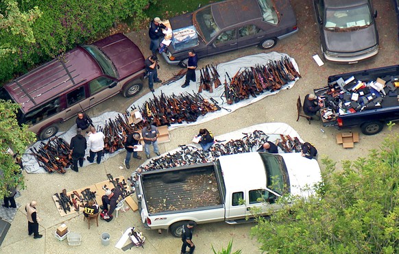 This photo from video provided by KCBS/KCAL-TV shows investigators from the U.S. Bureau of Alcohol, Tobacco, Firearms and Explosives and the police inspecting a large cache of weapons seized at a home ...
