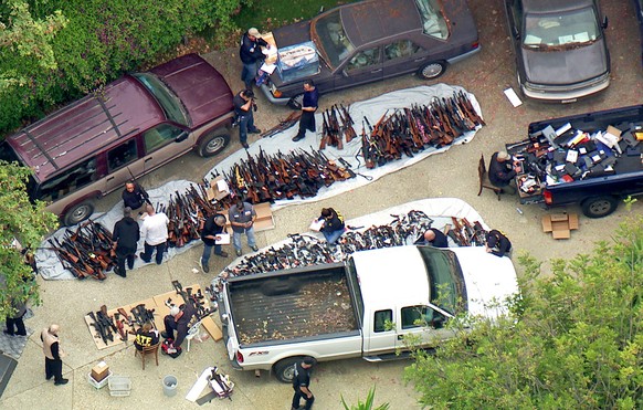 This photo from video provided by KCBS/KCAL-TV shows investigators from the U.S. Bureau of Alcohol, Tobacco, Firearms and Explosives and the police inspecting a large cache of weapons seized at a home ...