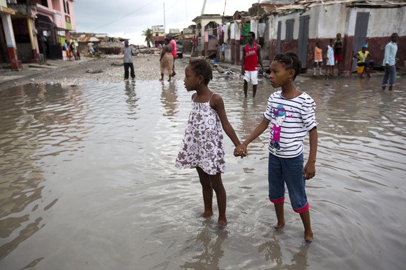 Girls hold hands as they help each other wade through a flooded street after the passing of Hurricane Matthew in Les Cayes, Haiti, Thursday, Oct. 6, 2016. Two days after the storm rampaged across the  ...