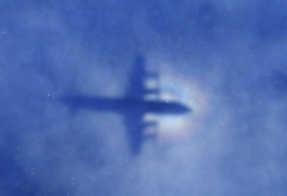 In this Monday, March 31, 2014 photo, a shadow of a Royal New Zealand Air Force P-3 Orion aircraft is seen on low cloud cover while it searches for missing Malaysia Airlines Flight MH370 in the southe ...