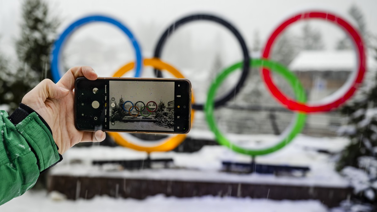A man takes a picture of the Olympic rings with his smartphone under the snow at the 2026 Olympic Winter Games in Cortina d'Ampezzo, Italy, on Wednesday, February 4, 2026. (KEYSTONE/Jean-Christop ...