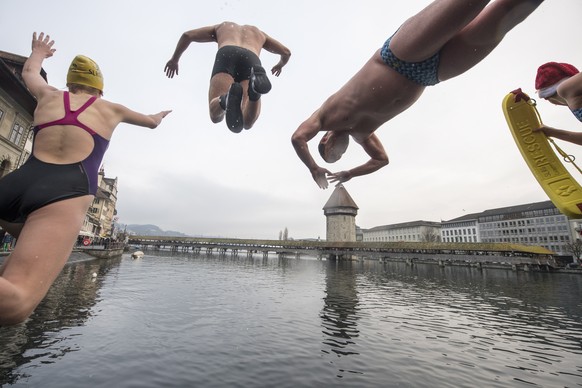 epa07255582 Approximately 40 lifeguards and swimmers of the Swiss Life Saving Society SLRG Lucerne Section celebrate New Year&#039;s Eve together with a jump into the Reuss river in the old town of Lu ...