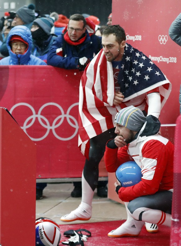 Chris Mazdzer of United States, standing, and David Gleirscher of Austria, watch Felix Loch of Germany&#039;s run during final heats of the men&#039;s luge competition at the 2018 Winter Olympics in P ...