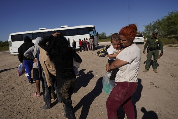 Migrants wait to board busses as they are processed by the U.S. Customs and Border Patrol after they crossed the Rio Grande and entered the U.S. from Mexico, Thursday, Oct. 19, 2023, in Eagle Pass, Te ...