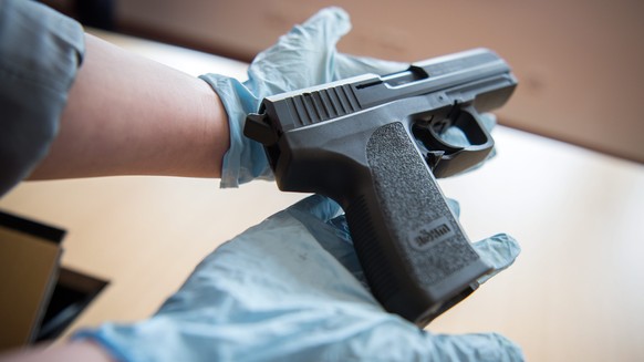 epa05187386 A member of the German Federal Criminal Police Office (BKA) holds up a gun taken into evidence, in Wiesbaden, Germany, 29 February 2016. Several pieces of evidence were seized and nine peo ...