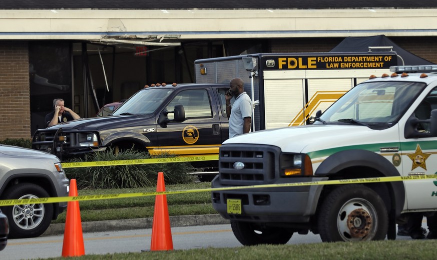 Law enforcement officers stand near a Florida Department of Law Enforcement vehicle that is parked in front of SunTrust Bank branch, Wednesday, Jan. 23, 2019, in Sebring, Fla., where authorities say f ...