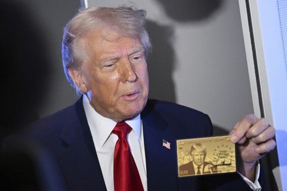 President Donald Trump holds up the $5 million gold card as he speaks to reporters while in flight on board Air Force One, en route to Miami, Thursday, April 3, 2025. (Pool via AP)