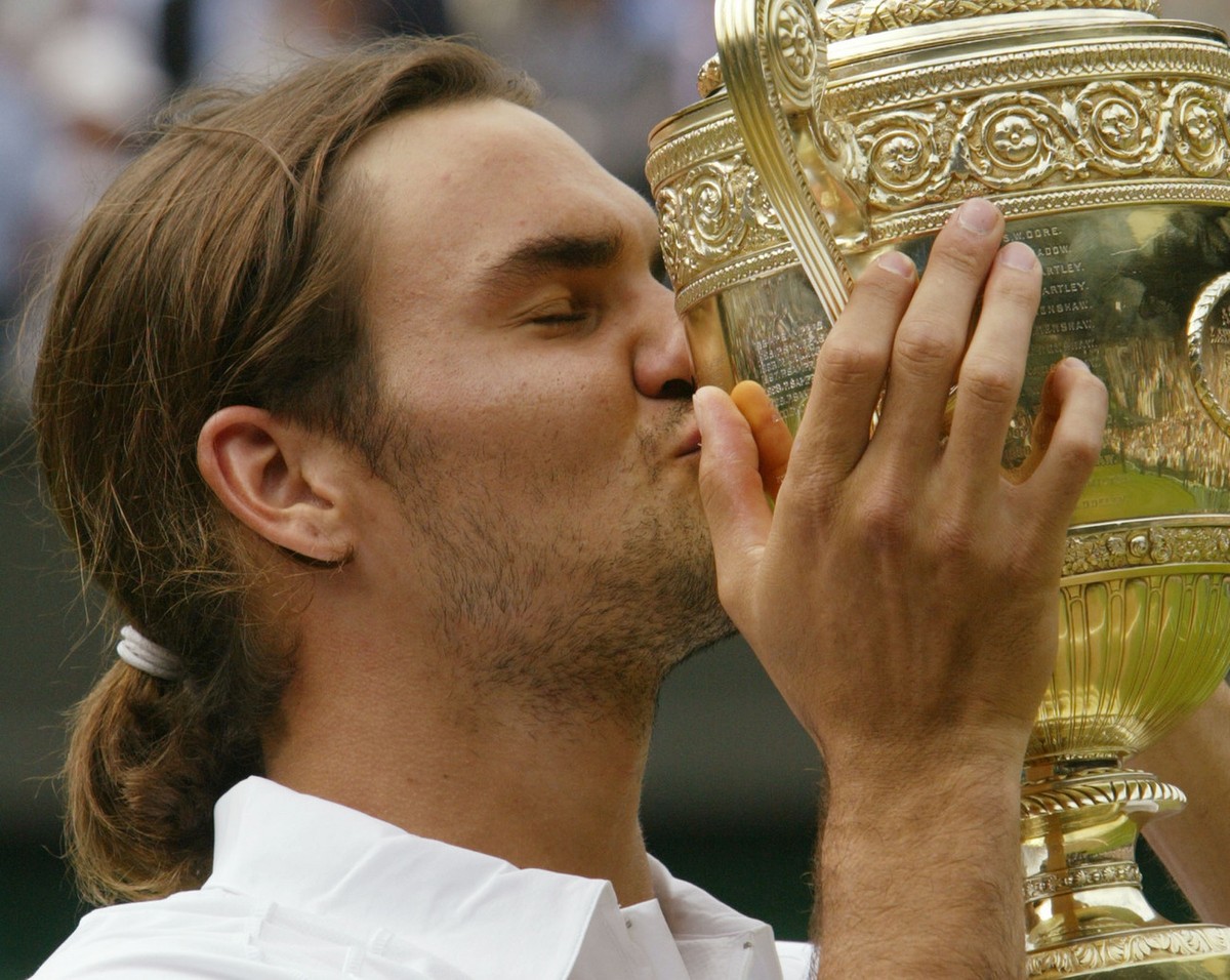 Switzerland's Roger Federer kisses the Men's Singles trophy after defeating Australia's Mark Philippoussis in the final of the All England Lawn Tennis Championships on the Centre Court  ...