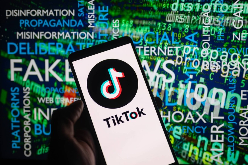 Social Media - Disinformation - Photo Illustration TikTok icon logo displayed on a smartphone with disinformation on screen seen in the background, in this photo illustration. On 15 October 2023, in B ...