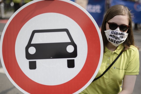 epa06120954 A protestor wears a mask and a cardboard reading &#039;Diesel-Abgase toeten! (Diesel emission kills), and holds a traffic sign meaning, &#039;passage for cars forbidden&#039; in front of t ...