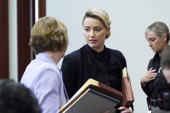 Actress Amber Heard talks to attorneys as lunch break starts, in the courtroom at the Fairfax County Circuit Courthouse in Fairfax, Va., Monday, April 25, 2022. Actor Johnny Depp sued his ex-wife Ambe ...