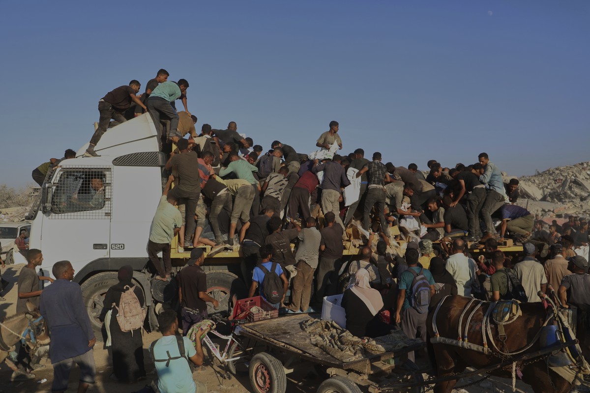 Palestinians struggle to get food and humanitarian aid from the back of a truck as it moves along the Morag corridor near Rafah, in the southern Gaza Strip, Monday, Aug. 4, 2025. (AP Photo/Mariam Dagg ...