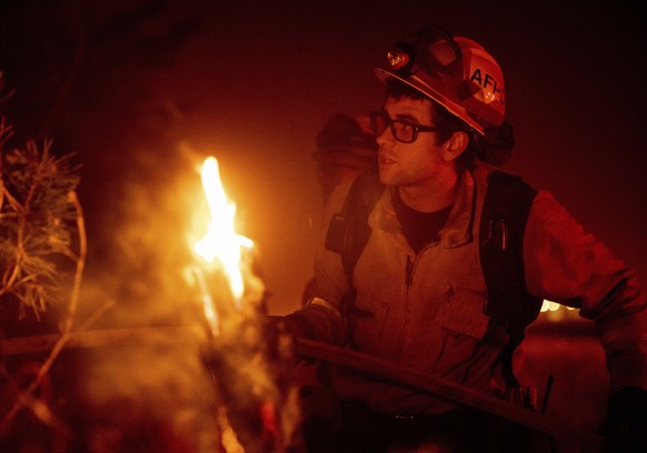 A firefighter battles the Dixie fire as it jumps Highway 395 south of Janesville, Calif., on Tuesday, Aug. 17, 2021. Critical fire weather throughout the region threatens to spread multiple wildfires  ...