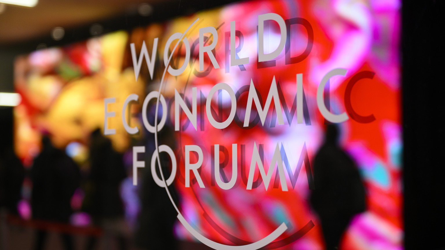 The logo of the WEF pictured on a window of the Congress Center as participants and artificial intelligence generated artwork by Turkish American media artist Refik Anadol are reflected inside the con ...