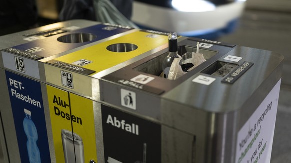 Eine Glasflasche kommt aus dem vollen Abfallbehaelter eines Abfalltrennungssystems, das Alu, PET und Abfall trennt, fotografiert am Mittwoch, 8. Mai 2024 in Zuerich (KEYSTONE/Gaetan Bally)