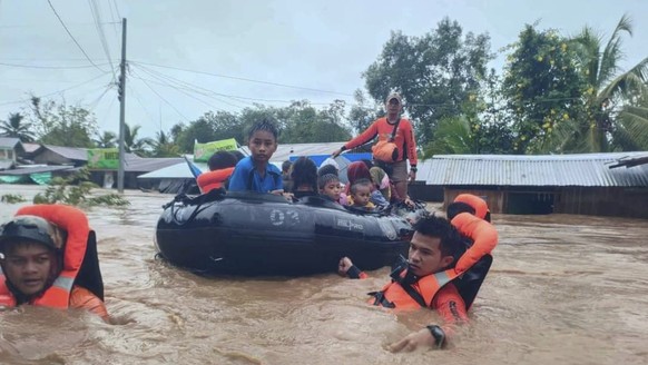 In this photo provided by the Philippine Coast Guard, rescuers use boats to evacuate residents from flooded areas due to Tropical Storm Nalgae at Parang, Maguindanao province, southern Philippines on  ...