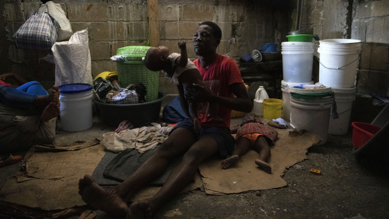 Ein Mann hält sein Baby in einer Auffangstation für Familien, die vor den <em>400 Mawozo</em> nach Port-au-Prince geflüchtet sind.