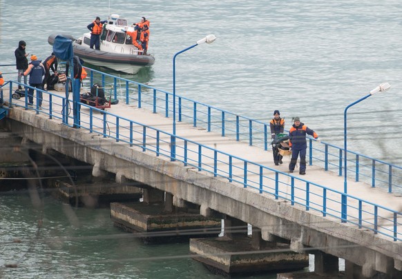 epa05687865 Rescuers unload fragments and remains from a boat, found at the site of the Tu-154 plane crash near Sochi, Russia, 25 December 2016. According to media reports, a Tupolev-154 Russian airpl ...