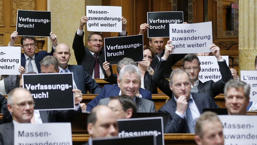 Nationalraete der SVP halten Plakate mit der Aufschrift &quot;Verfassungsbruch&quot; und &quot;Massenzuwanderung geht weiter&quot; hoch, bei der Schlussabstimmung ueber die Masseneinwanderungsinitiati ...