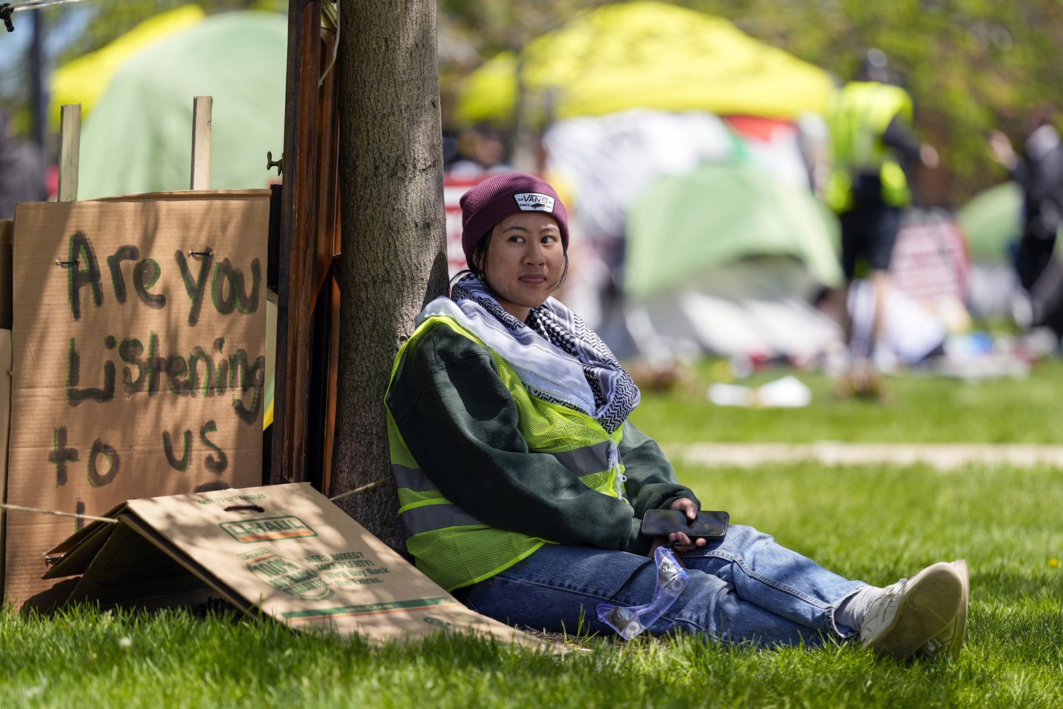 FILE - A woman sits outside an encampment area on the University of Wisconsin-Milwaukee campus, Tuesday, April 30, 2024, in Milwaukee. The Pro-Palestinian rally is calling for the University to cut ti ...
