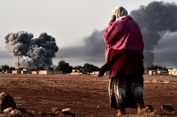 Rauch steigt auf aus der belagerten Stadt Kobane – eine kurdische Frau beobachtet die Luftangriffe auf IS-Stellungen.&nbsp;