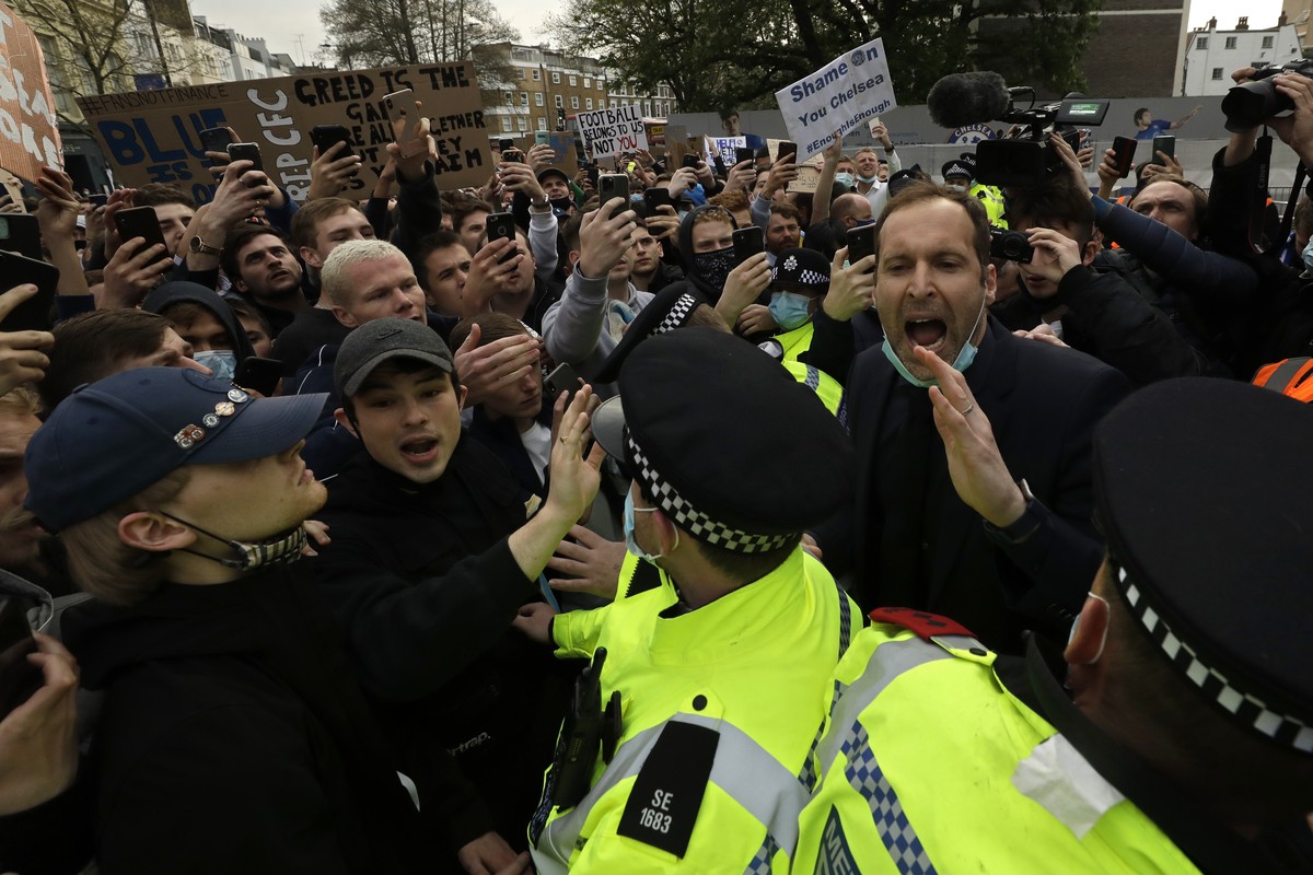 Chelsea former star goalkeeper Petr Cech, at right, behind a line of policemen, tries to calm down fans protesting outside Stamford Bridge stadium in London, against Chelsea's decision to be incl ...
