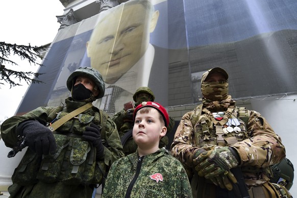 A boy and Russian soldiers take part in an action to mark the ninth anniversary of the Crimea annexation from Ukraine, in Yalta, Crimea, Friday, March 17, 2023. (AP Photo)