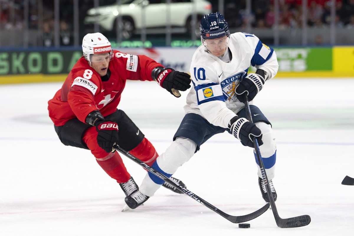 epa12995900 Switzerland's Simon Knak, left, fights for the puck against Finland's Henri Jokiharju, right, during the 2026 IIHF Men's Ice Hockey World Championship preliminary round grou ...