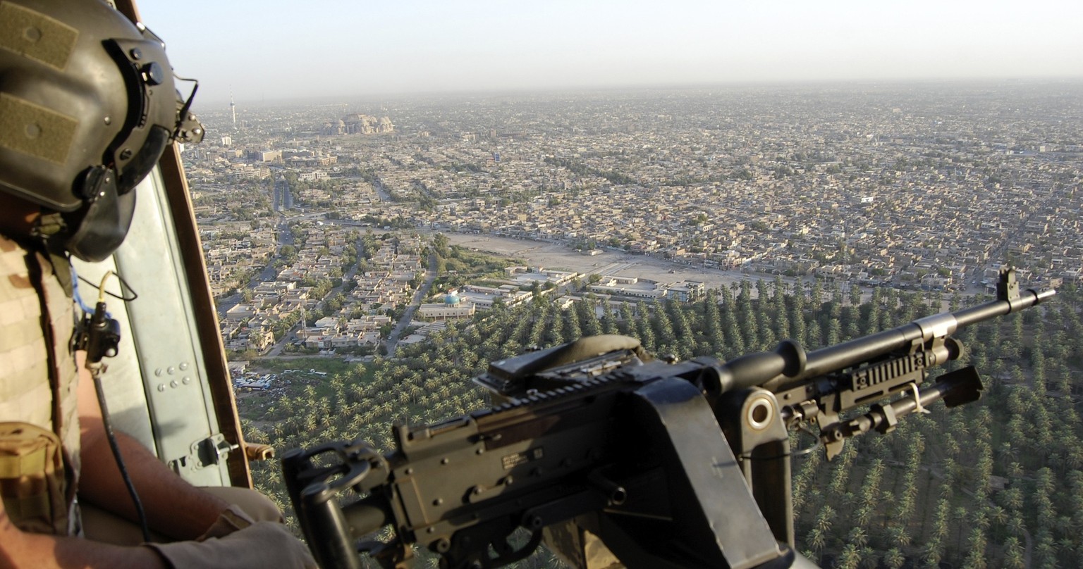 A member of the Iraqi Air Force looks out of a military helicopter at an aerial view of Baghdad, June 26, 2014. Picture taken June 26, 2014. REUTERS/Stringer (IRAQ - Tags: CIVIL UNREST POLITICS MILITA ...