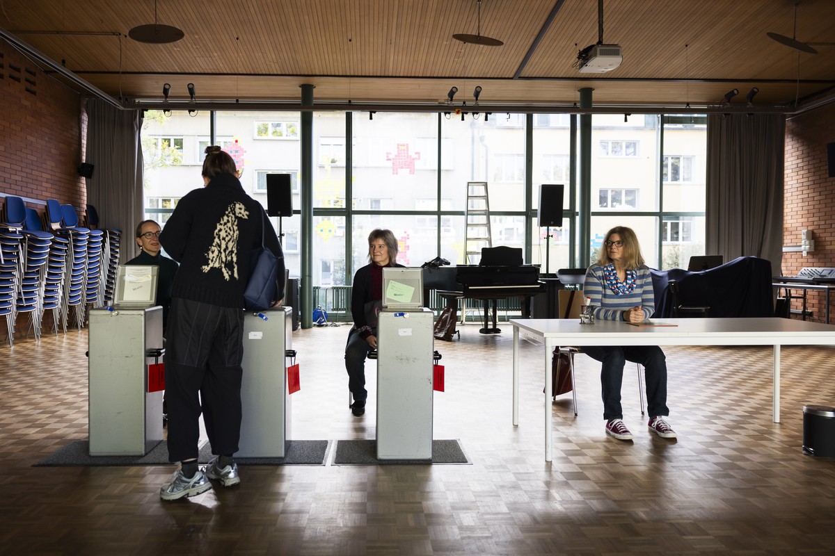 Eine Waehlerin, links, wirft ihren Wahlzettel neben Wahlhelferinnen in eine Urne im Stimmlokal im Schulhaus Hochfeld, am Wahltag der Eidgenoessischen Parlamentswahlen, am Sonntag, 22. Oktober 2023 in  ...
