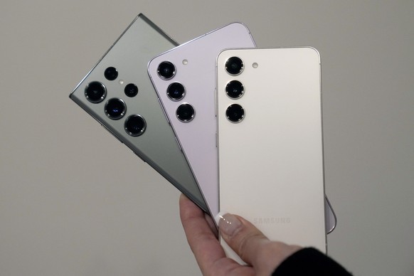 A green Samsung Galaxy S23 Ultra phone, left, lavender S23 Plus phone, middle, and cream S23 phone are held in San Francisco, Tuesday, Jan. 31, 2023. (AP Photo/Jeff Chiu)