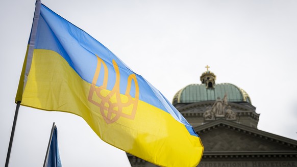Eine ukrainische Flagge vor der Kuppel des Bundeshauses, waehrend einer nationalen Solidaritaetskundgebung fuer einen gerechten Frieden in der Ukraine am Samstag, den 22. $February 2025, in Bern. Der  ...