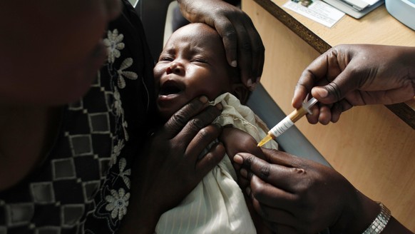 FILE - A mother holds her baby receiving a new malaria vaccine as part of a trial at the Walter Reed Project Research Center in Kombewa in Western Kenya on Oct. 30, 2009. Cameroon is beginning the wor ...