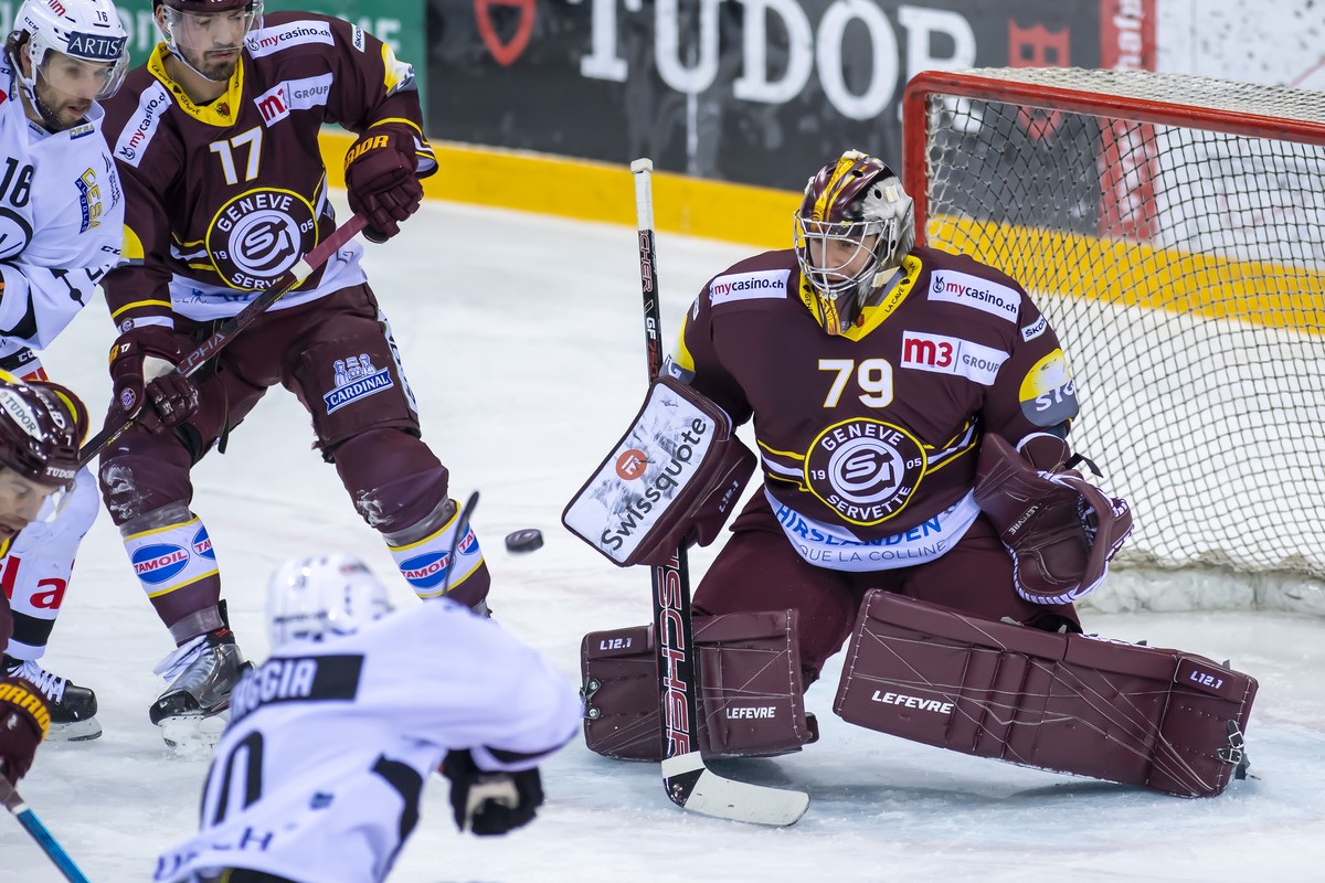 L'attaquant luganais Alessio Bertaggia, gauche, a la lutte pour le puck avec le gardien genevois Daniel Manzato, droite, lors du match du championnat suisse de hockey sur glace de National League ...