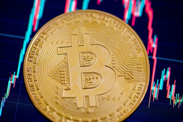 ARCHIV - 22.05.2023, Berlin: Eine Bitcoin-M�nze liegt auf einem Bildschirm, der den Bitcoin - US-Dollar Kurs zeigt. Die US-B�rsenaufsicht SEC hat nach langem Z�gern nun doch gr�nes Licht f�r Bitcoin-E ...