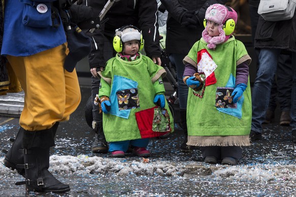 Kinder verfolgen das bunte Treiben an der Fasnacht, am Sonntag, 1. Februar 2015, in Thun. (KEYSTONE/Peter Schneider)