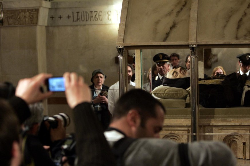 Pilgrims photograph the body of Padre Pio, an Italian saint, laying in repose inside a crystal casket in the crypt of the church of Santa Maria delle Grazie in San Giovanni Rotondo, Italy, Thursday, A ...