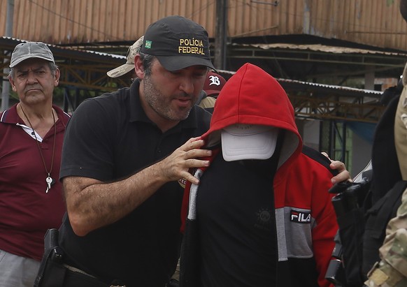 A federal police officer escorts a suspect towards a river in the area where Indigenous expert Bruno Pereira and freelance British journalist Dom Phillips disappeared, in Atalaia do Norte, Amazonas st ...