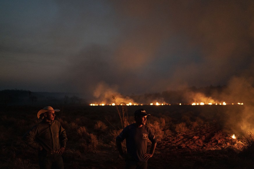 Neri dos Santos Silva, center, watches an encroaching fire threat after digging trenches to keep the flames from spreading to the farm he works on, in the Nova Santa Helena municipality, in the state  ...