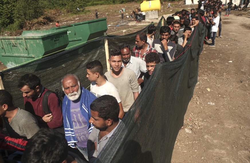 In this photo taken on Wednesday, June 19, 2019, migrants wait in line to receive supplies from the Red Cross at the Vucijak camp outside Bihac, Bosnia. Still deeply scarred by a brutal inter-ethnic w ...