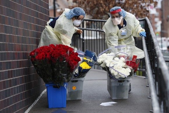 Emergency room nurses transport buckets of donated flowers up a ramp outside Elmhurst Hospital Center&#039;s emergency room, Saturday, March 28, 2020, in New York. The hospital has been heavily taxed  ...