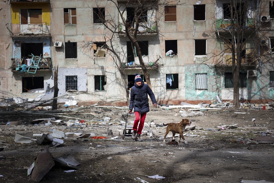 A man walks with his dog near an apartment building damaged by shelling from fighting on the outskirts of Mariupol, Ukraine, in territory under control of the separatist government of the Donetsk Peop ...