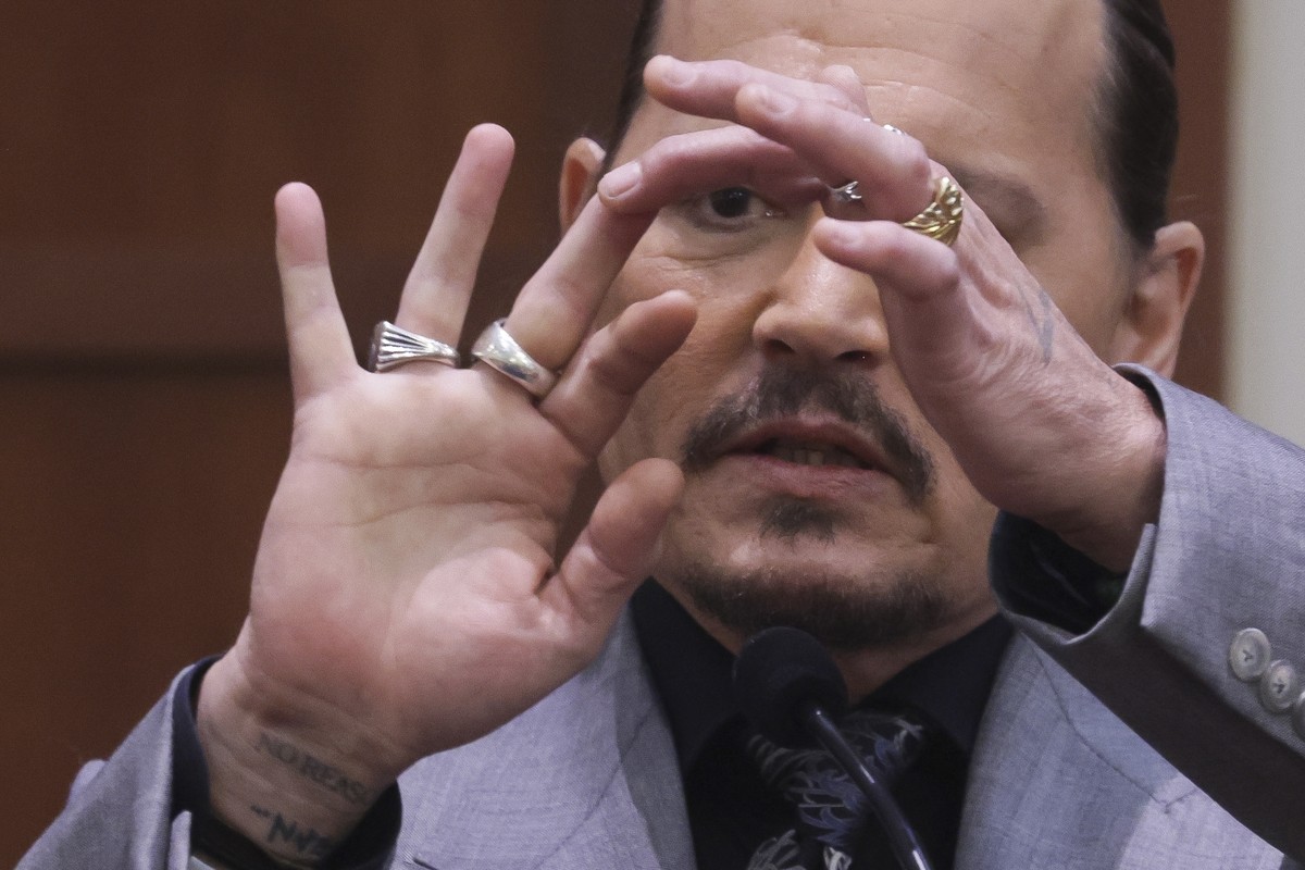 epa09899091 Actor Johnny Depp displays the middle finger of his hand, injured while he and his ex-wife Amber Heard were in Australia in 2015, as he testifies during his defamation trial against Heard  ...