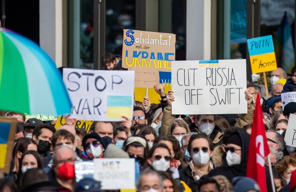 epa09786593 Demonstrators hold up placards reading &#039;Stop War&#039; (L), &#039;Solidarity with Ukraine&#039; (C) and &#039;Cut Russia off SWIFT&#039; (R) during a demonstration against Russia&#039 ...