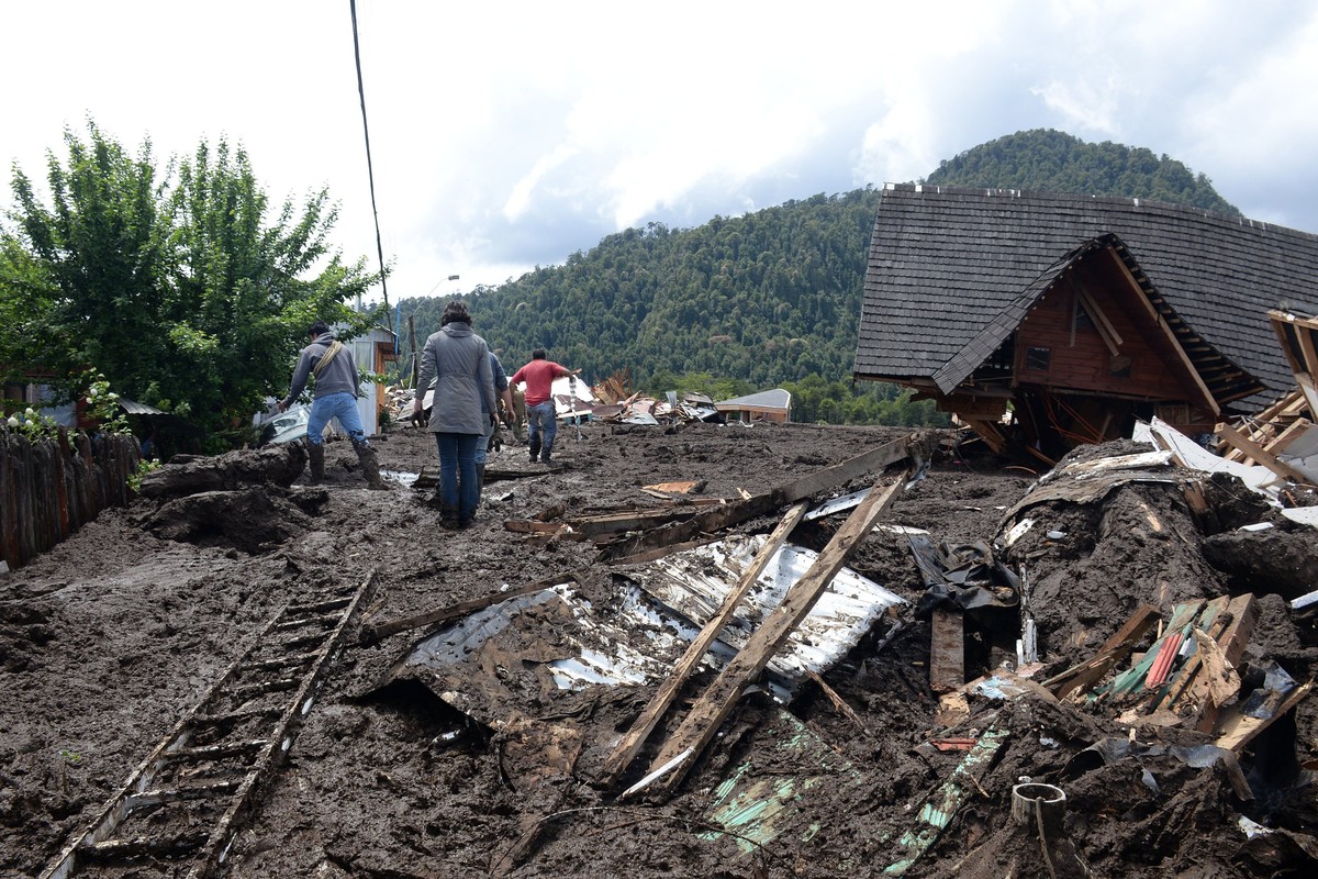 epa06394524 A handout photo made available by the Intendency of the Los Lagos Region shows a group of people that observe the damage after an landslide that caused the death of at least three people,  ...