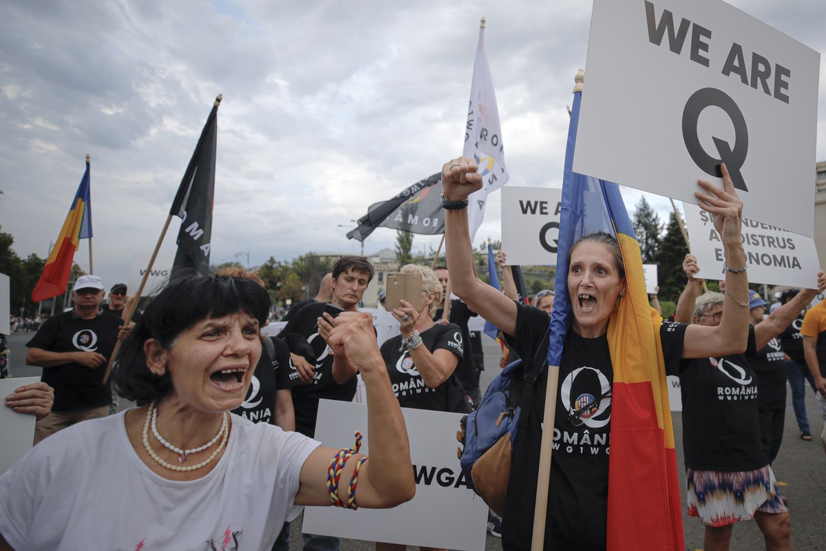 Romanian supporters of QAnon shout slogans against the government's measures to prevent the spread of COVID-19 infections, like wearing a face mask, during a rally in Bucharest, Romania, Monday,  ...