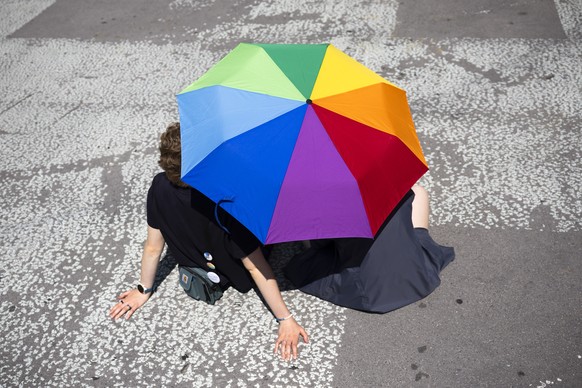 epa12279525 Two persons sit under an umbrella in rainbow colors during the Pride Parade in Bern, Switzerland, 02 August 2025. EPA/PETER KLAUNZER