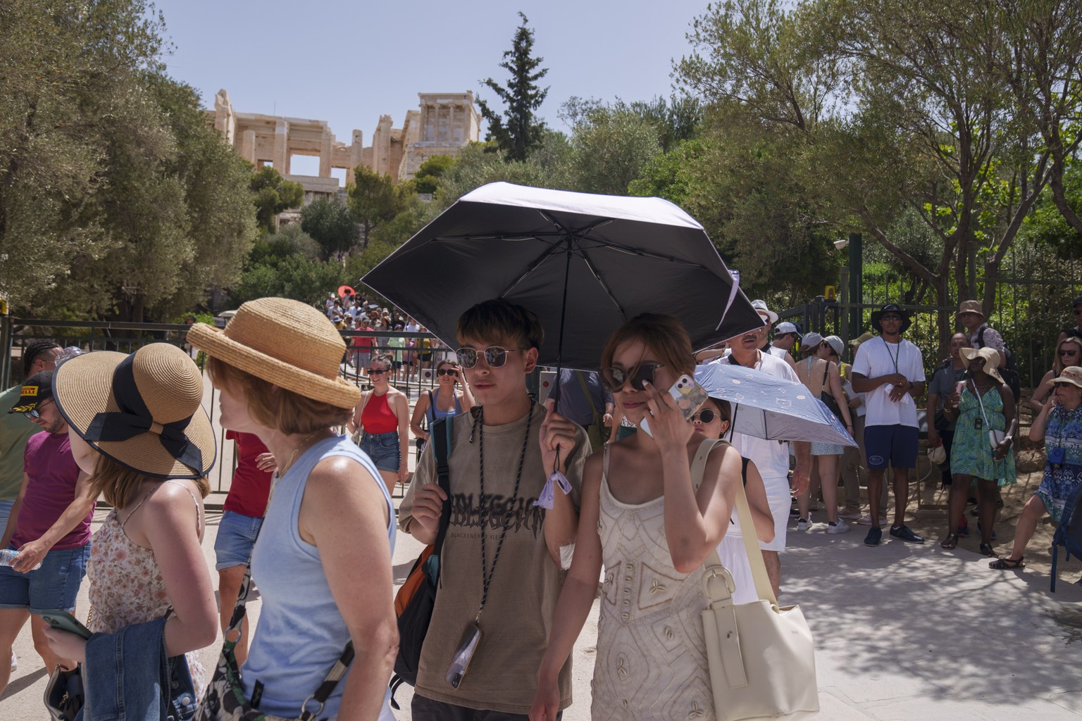 Tourists exit the ancient Acropolis in central Athens on Wednesday, June 12, 2024. The ancient site was closed to the public for five hours due to a heat wave that pushed temperatures to 39 degrees Ce ...